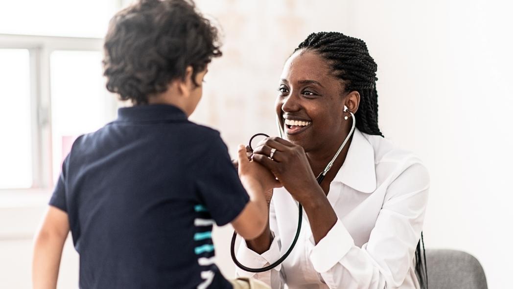 black, female doctor examining a pediatric male patient