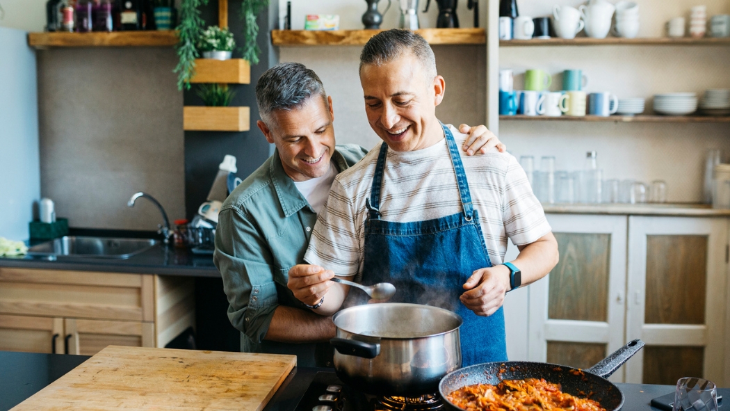 Gay couple cooking together in a kitchen.